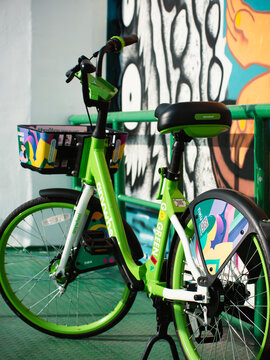 Close-up detail of green Anywheel Bangkok BMA public shared bicycle rental frame with brand logo and colorful graphic artwork sticker design