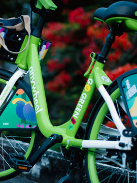 Close-up detail of green Anywheel Bangkok BMA public shared bicycle rental frame with brand logo and colorful graphic artwork sticker design