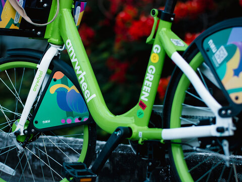 Close-up detail of green Anywheel Bangkok BMA public shared bicycle rental frame with brand logo and colorful graphic artwork sticker design