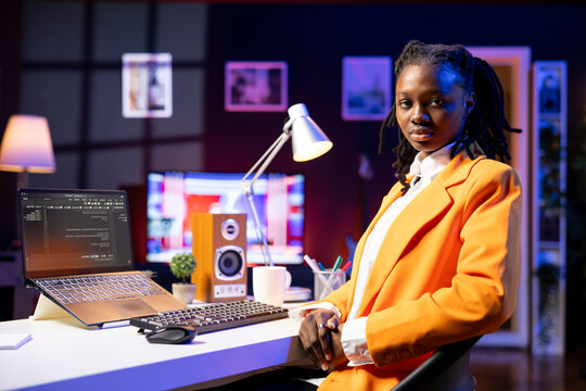 Portrait of programmer at desk typing code on laptop, developing software programs, entering commands, african American woman at home fixing errors in application, implementing new features.