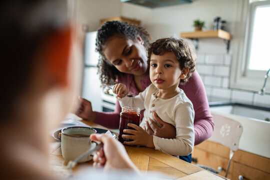 Mother and toddler spooning jam in home kitchen