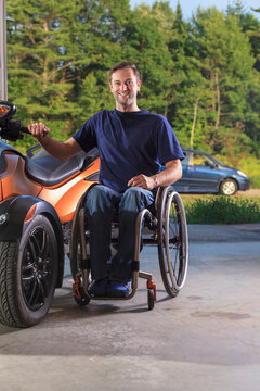 Man with spinal cord injury sitting in wheelchair beside his custom motorcycle