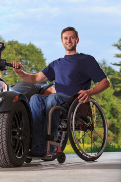 Man with spinal cord injury sitting in wheelchair beside his custom motorcycle