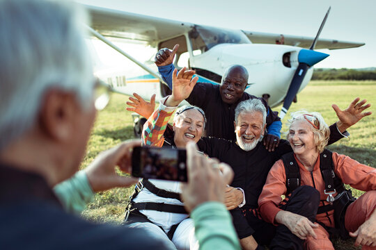 Senior friends posing after skydiving at airfield
