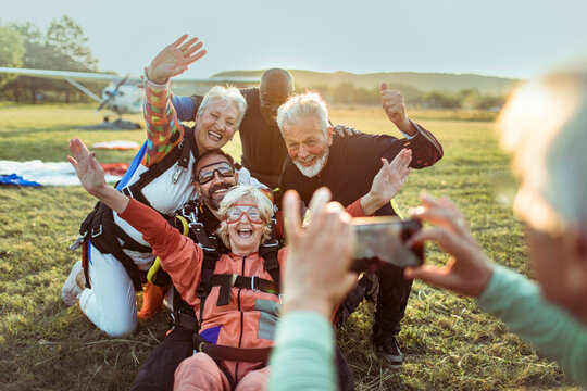 Group of happy seniors celebrating skydiving at airfield
