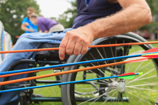 Man with spinal cord injury in wheelchair removing arrows from target after archery practice