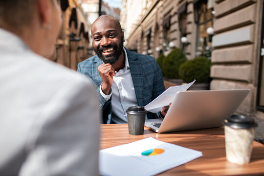 Smiling businessman presenting charts at outdoor cafe