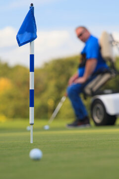 Man with spinal cord injury in an adaptive cart at golf putting green