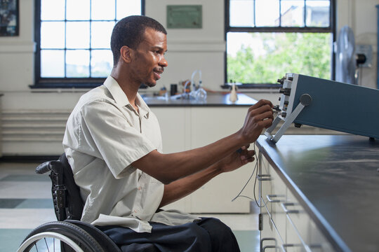 Student who had Spinal Meningitis setting up oscilloscope to use photo detector in laboratory