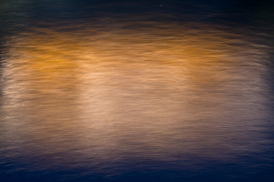 Abstract ICM (Intentional Camera Movement) featuring fluid copper and amber light trails blending into indigo. A painterly texture with soft grain, suggesting energy and innovation.
