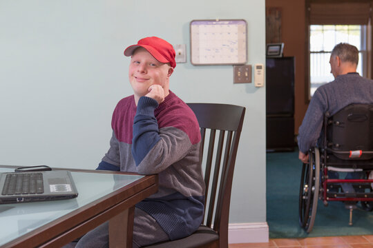 Happy young man with Down Syndrome and his father in wheelchair with Spinal Cord Injury at home