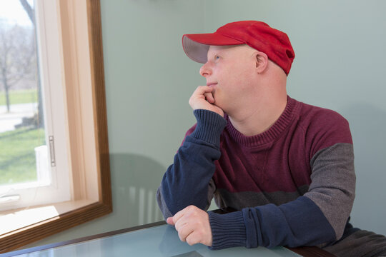 Happy young man with Down Syndrome sitting at home