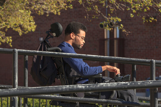 African American man with Cerebral Palsy using his power wheelchair outside