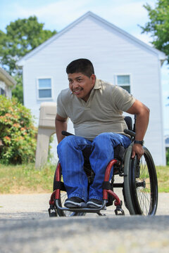 Hispanic man with Spinal Cord Injury on wheelchair in front of his house