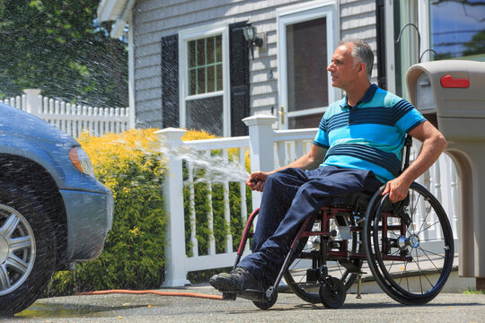 Man with a Spinal Cord Injury in wheelchair washing his accessible car