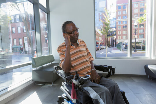 Man with Guillain-Barre Syndrome on wheelchair in front of the apartment window