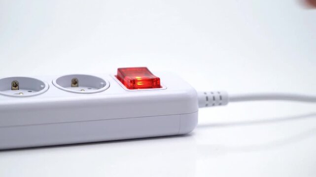 A hand switches on a white electrical power outlet with a red switch in a close-up video.