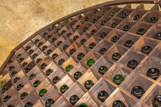 A wine cellar in the ancient basement of a medieval house.  There are bottles of wine on the shelves in the cellar. A vaulted stone basement in an old house.