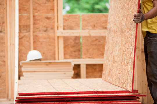 Hispanic carpenter picking up roof panels at a house under construction