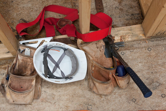 Close-up of tool belt with tools and a hard hat at a construction site