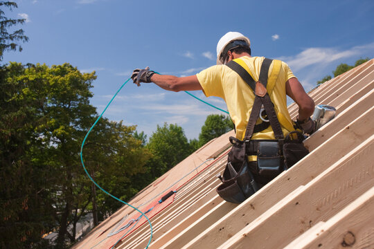 Hispanic carpenter untangling air hose at a house under construction