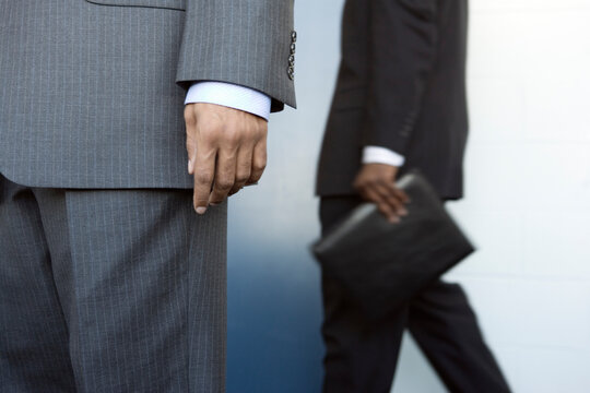Two businessmen standing by a wall