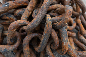 Fototapeta premium Close-up of a heavy rusty iron chain tangled in a pile on a ground