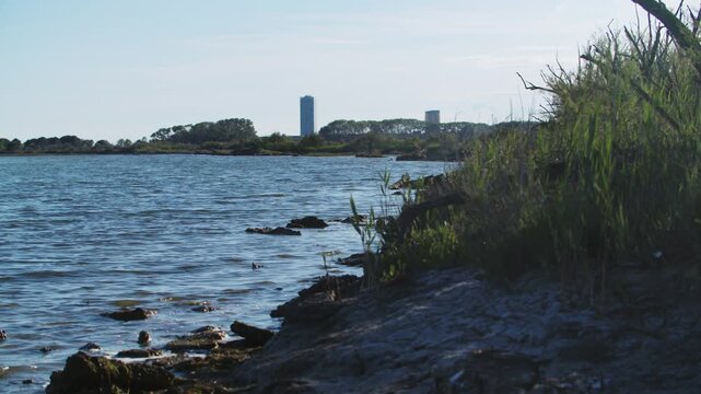 coastline from Eraclea Mare towards the distant Jesolo beach resort skyline at sunset, showing the calm sea surface and sandy coastal shore, Italy established shot