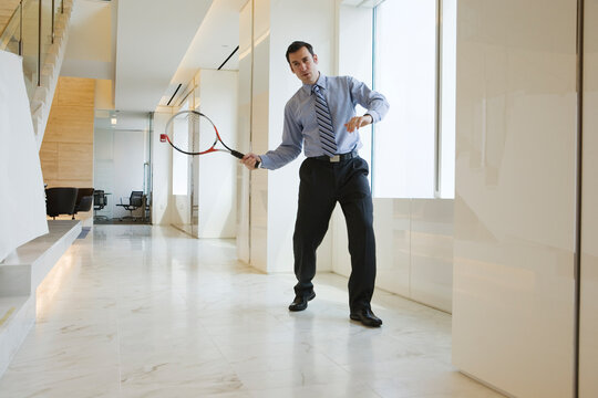 Businessman holding a racquet in an office