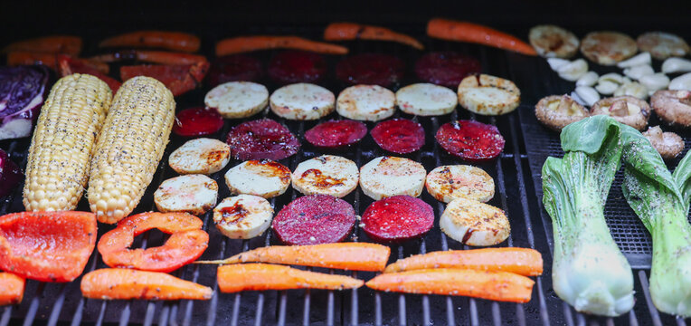 Farm fresh garden vegetables cooking on a pellet grill smoker for a vegetarian dinner. The healthy food is colorful and packed with vitamins and garden nutrients. Delicious!