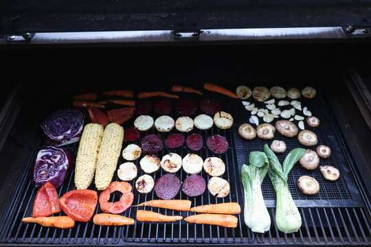 Farm fresh garden vegetables cooking on a pellet grill smoker for a vegetarian dinner. The healthy food is colorful and packed with vitamins and garden nutrients. Delicious!