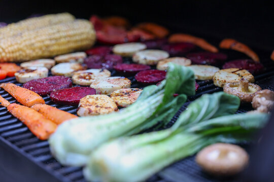Farm fresh garden vegetables cooking on a pellet grill smoker for a vegetarian dinner. The healthy food is colorful and packed with vitamins and garden nutrients. Delicious!