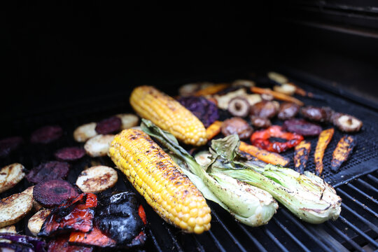 Farm fresh garden vegetables cooking on a pellet grill smoker for a vegetarian dinner. The healthy food is colorful and packed with vitamins and garden nutrients. Delicious!