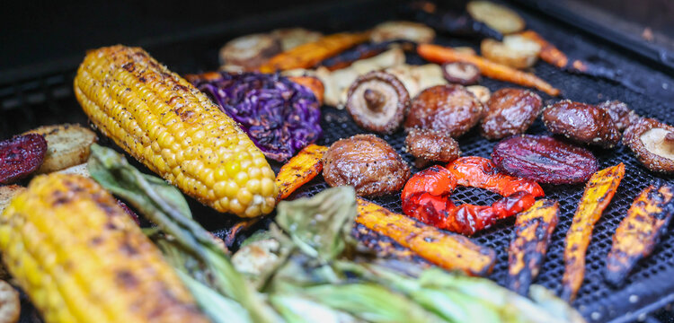 Farm fresh garden vegetables cooking on a pellet grill smoker for a vegetarian dinner. The healthy food is colorful and packed with vitamins and garden nutrients. Delicious!
