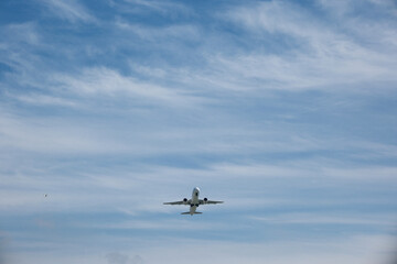 Fototapeta premium Front view of a commercial jet airplane climbing after takeoff against blue sky with white clouds