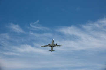 Fototapeta premium Front view of a commercial jet airplane climbing after takeoff against blue sky with white clouds