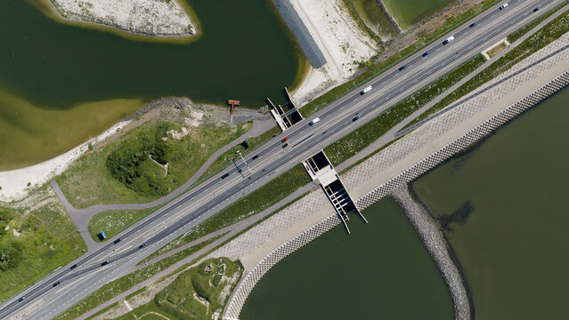 Aerial view of the Vismigratierivier fish migration passage and the Afsluitdijk highway with cars driving across the water in Kornwerderzand, Friesland, Netherlands.