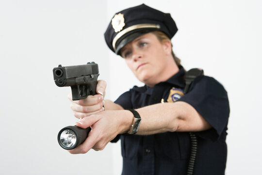 Police woman pointing handgun and holding flashlight
