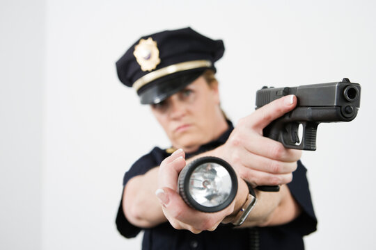 Police woman pointing handgun and holding flashlight