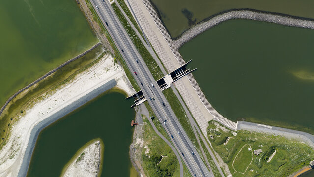 Aerial view of the Vismigratierivier fish migration river crossing the Afsluitdijk with a highway and stone embankments in Kornwerderzand, Friesland, Netherlands.