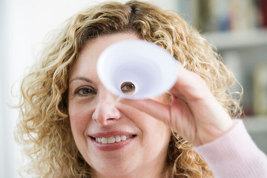 Portrait of a mature woman peeping through a rolled up paper