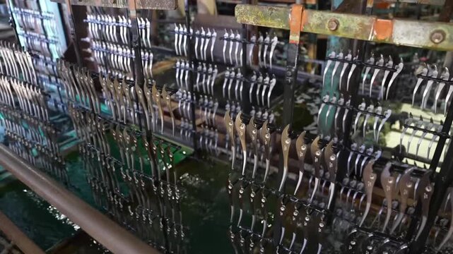 Pliers racks dipping into dark acid pickling bath with pipes and industrial equipment