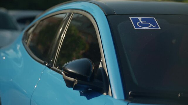 Handicap parking permit displayed on a blue parked car windshield in city street