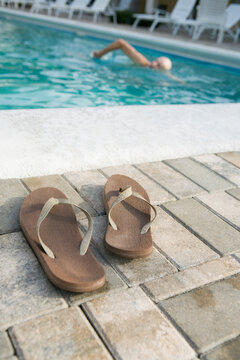 Pair of flip-flops on the ledge of a swimming pool