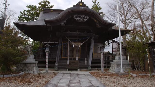 Wide static shot of a traditional Shinto shrine in Japan under a cloudy sky.