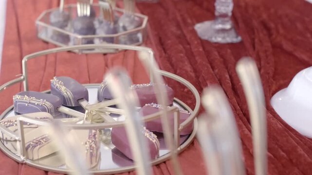 Handheld parallax close-up of pastel desserts on mirrored tray at event setup