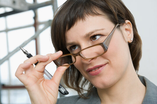 Close-up of a businesswoman holding eyeglasses and smirking