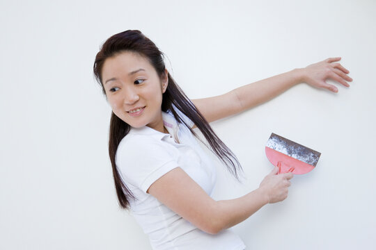 Side profile of a young woman scraping paint on wall