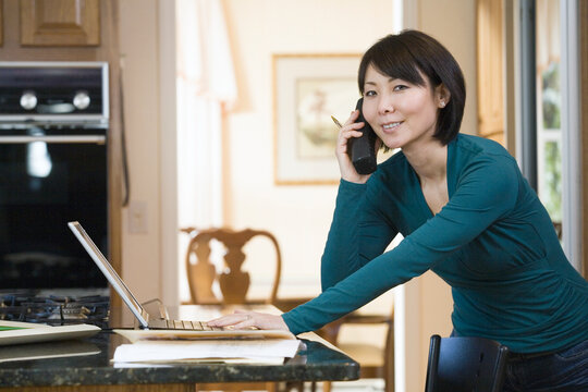 Portrait of a mid adult woman using a laptop and talking on a mobile phone