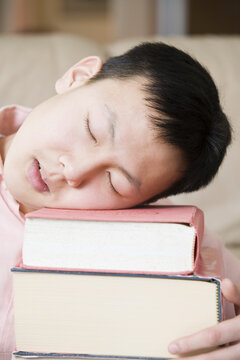 Close-up of a teenage boy sleeping on a stack of books
